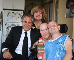 Picture of Stephen Raynes and Mercedes Benegbi with a thalidomide survivor and her husband. Photo taken in their home kitchen.