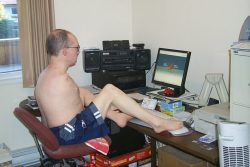 Homme n'ayant pas de bras utilisant un ordinateur avec ses pieds.